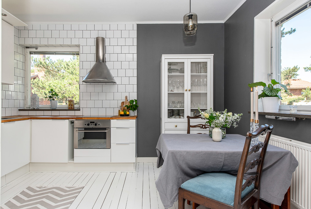 Esempio di una cucina abitabile scandinava di medie dimensioni con ante lisce, ante bianche, pavimento in legno verniciato, pavimento bianco, top in legno, paraspruzzi bianco e elettrodomestici in acciaio inossidabile