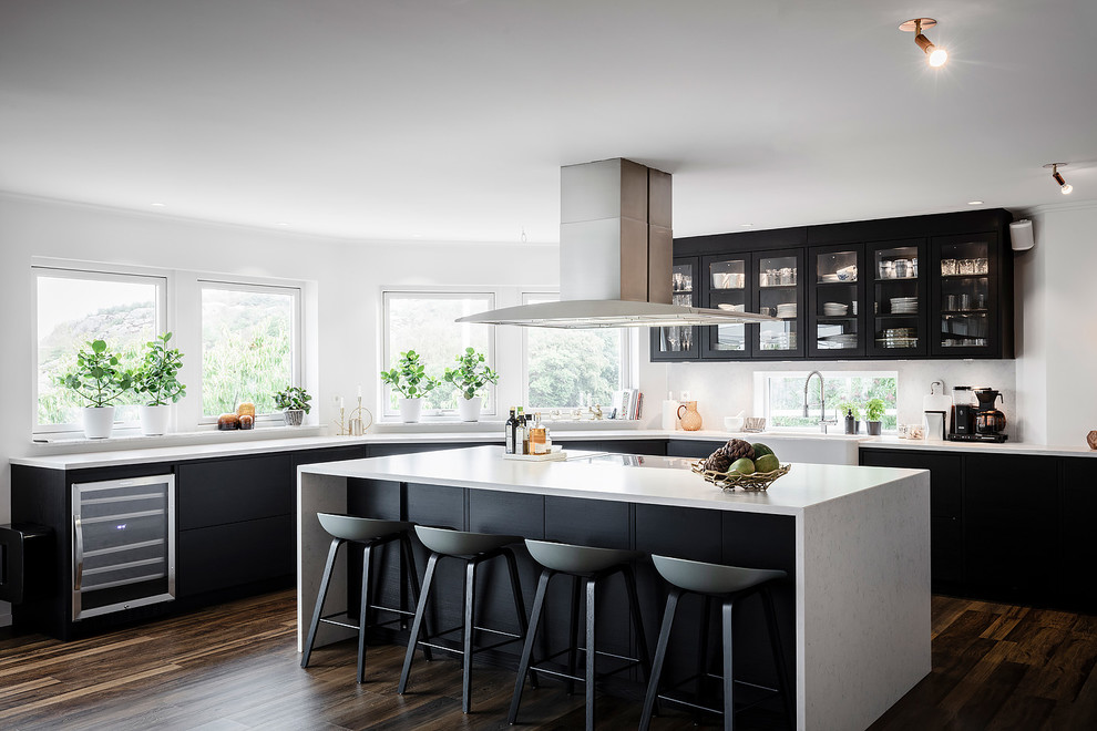 Immagine di una grande cucina scandinava con ante di vetro, ante nere, lavello stile country, parquet scuro, pavimento marrone e top bianco