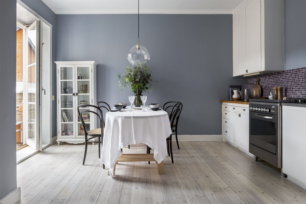 Scandinavian kitchen in Stockholm with flat-panel cabinets, white cabinets, light hardwood flooring and no island.