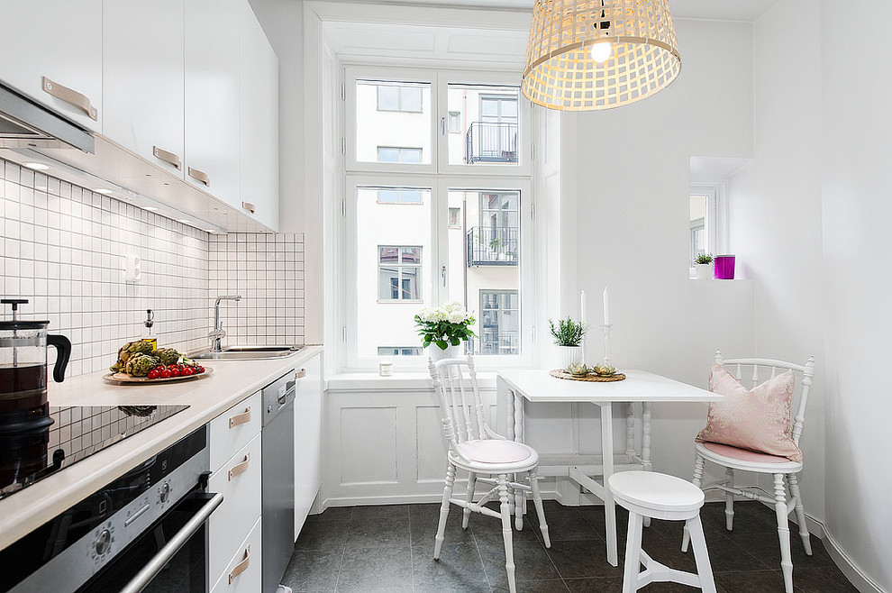 Foto på ett mellanstort skandinaviskt linjärt kök och matrum, med en dubbel diskho, släta luckor, vita skåp, vitt stänkskydd, rostfria vitvaror och klinkergolv i keramik
