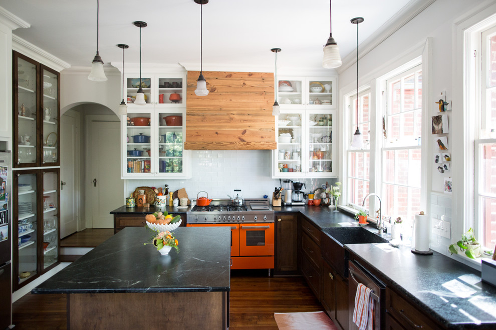 Mittelgroße Urige Küche in L-Form mit Landhausspüle, Glasfronten, weißen Schränken, bunten Elektrogeräten, braunem Holzboden, Kücheninsel und Granit-Arbeitsplatte in Sonstige