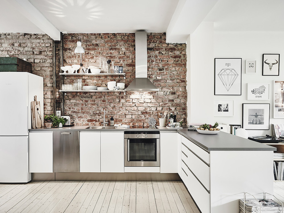 Nordisk inredning av ett mellanstort linjärt kök och matrum, med en enkel diskho, släta luckor, vita skåp, bänkskiva i betong, rostfria vitvaror och ljust trägolv