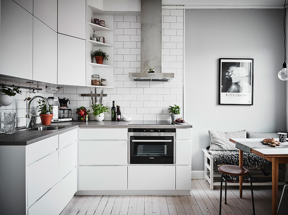 Inspiration for an industrial kitchen in Gothenburg with flat-panel cabinets, white cabinets and no island.