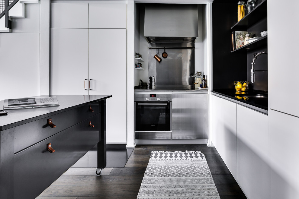 Foto på ett mellanstort skandinaviskt kök, med en nedsänkt diskho, bänkskiva i kalksten, integrerade vitvaror, mörkt trägolv, en köksö, släta luckor, vita skåp och stänkskydd med metallisk yta