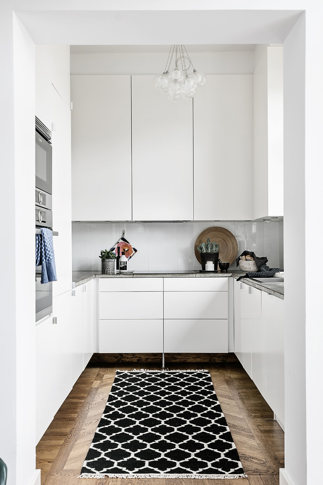 Пример оригинального дизайна: п-образная кухня-гостиная в скандинавском стиле с плоскими фасадами, белыми фасадами и столешницей из бетона