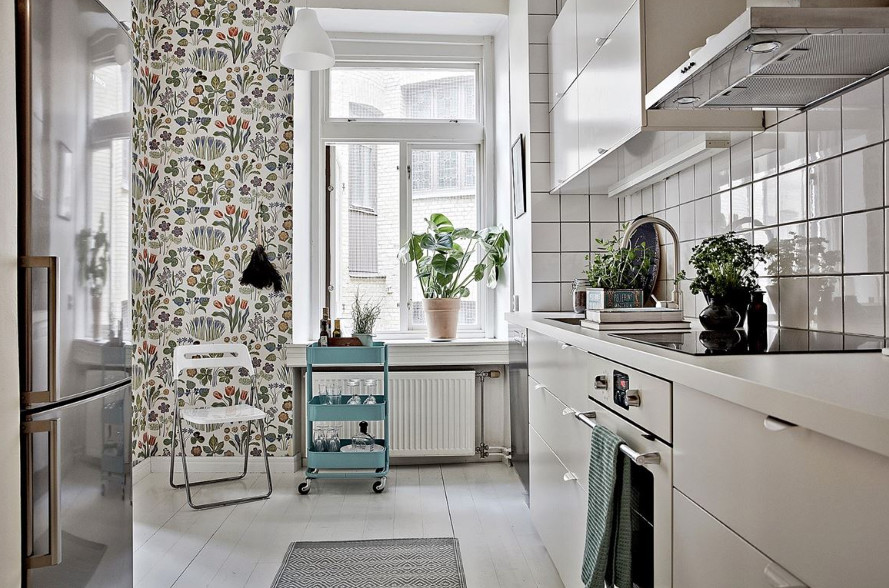 Ejemplo de cocina lineal escandinava pequeña cerrada sin isla con armarios con paneles lisos, puertas de armario blancas, encimera de acrílico, salpicadero blanco y salpicadero de azulejos tipo metro