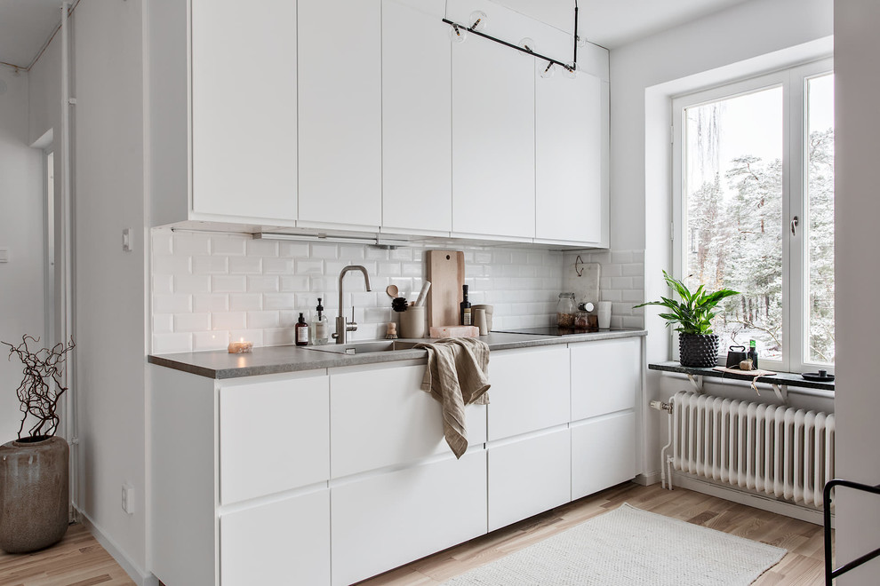 Inspiration för ett nordiskt kök, med släta luckor, vita skåp, bänkskiva i betong, en enkel diskho, vitt stänkskydd, stänkskydd i tunnelbanekakel, ljust trägolv och beiget golv