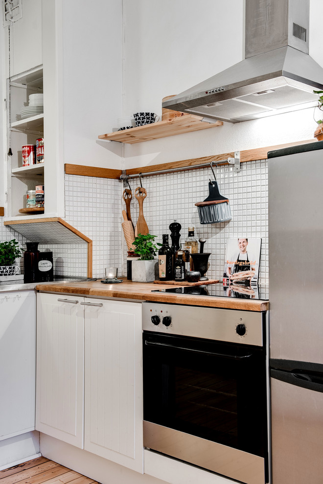 Foto di una piccola cucina scandinava chiusa con top in legno, paraspruzzi grigio, elettrodomestici in acciaio inossidabile, parquet chiaro e nessuna isola