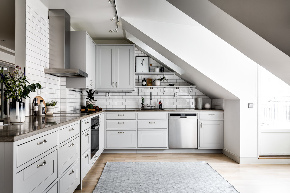 Foto på ett mellanstort minimalistiskt brun kök, med grå skåp, träbänkskiva, vitt stänkskydd, stänkskydd i tunnelbanekakel, rostfria vitvaror och ljust trägolv