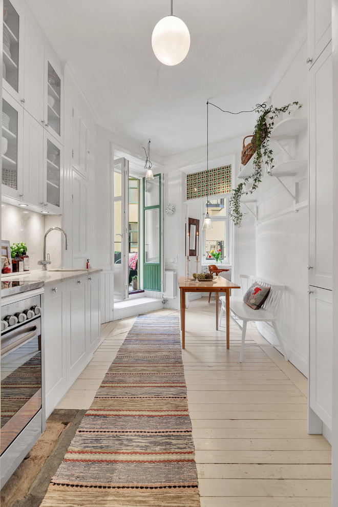 Inredning av ett skandinaviskt mellanstort linjärt kök och matrum, med en enkel diskho, luckor med infälld panel, vita skåp, rostfria vitvaror, ljust trägolv och beiget golv