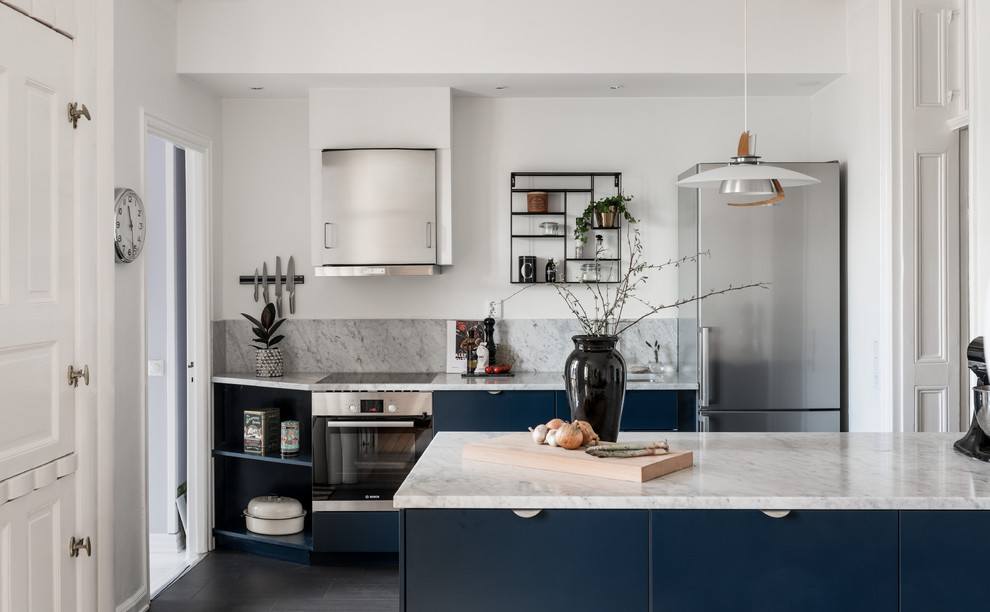 Inspiration for a scandi galley kitchen in Stockholm with a submerged sink, flat-panel cabinets, blue cabinets, marble worktops, grey splashback, marble splashback, stainless steel appliances, a breakfast bar, black floors and grey worktops.