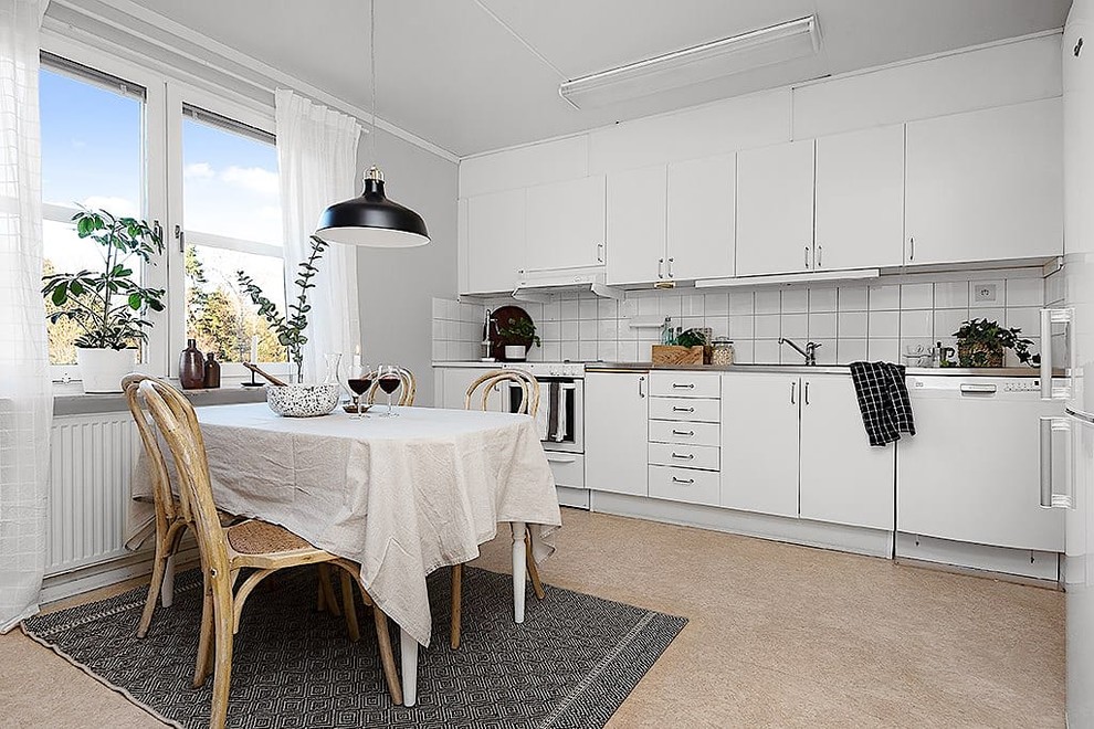 Idéer för ett minimalistiskt kök och matrum, med släta luckor, vita skåp, bänkskiva i rostfritt stål, vitt stänkskydd, vita vitvaror och beiget golv