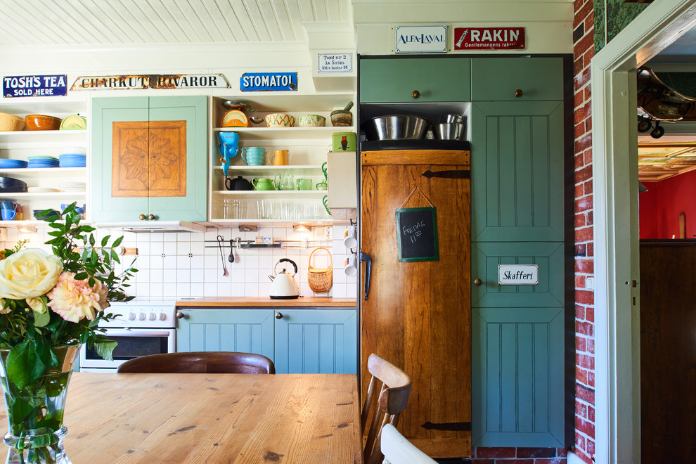 Einzeilige Eklektische Wohnküche mit Schrankfronten im Shaker-Stil, blauen Schränken, Küchenrückwand in Weiß und Elektrogeräten mit Frontblende in Göteborg