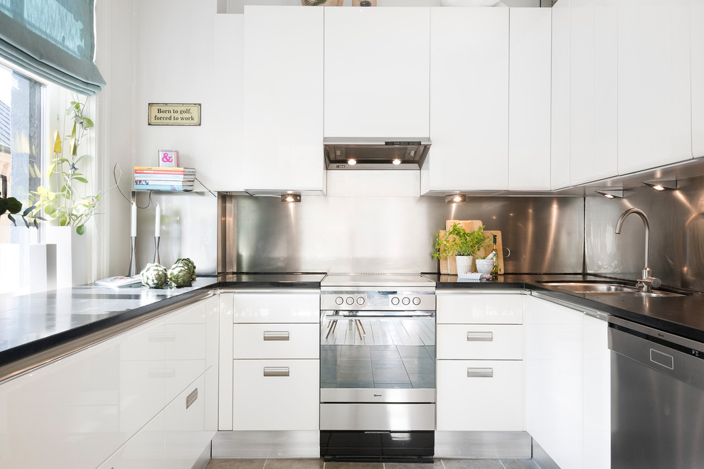 Idéer för att renovera ett minimalistiskt u-kök, med en undermonterad diskho, släta luckor, vita skåp, stänkskydd med metallisk yta och rostfria vitvaror