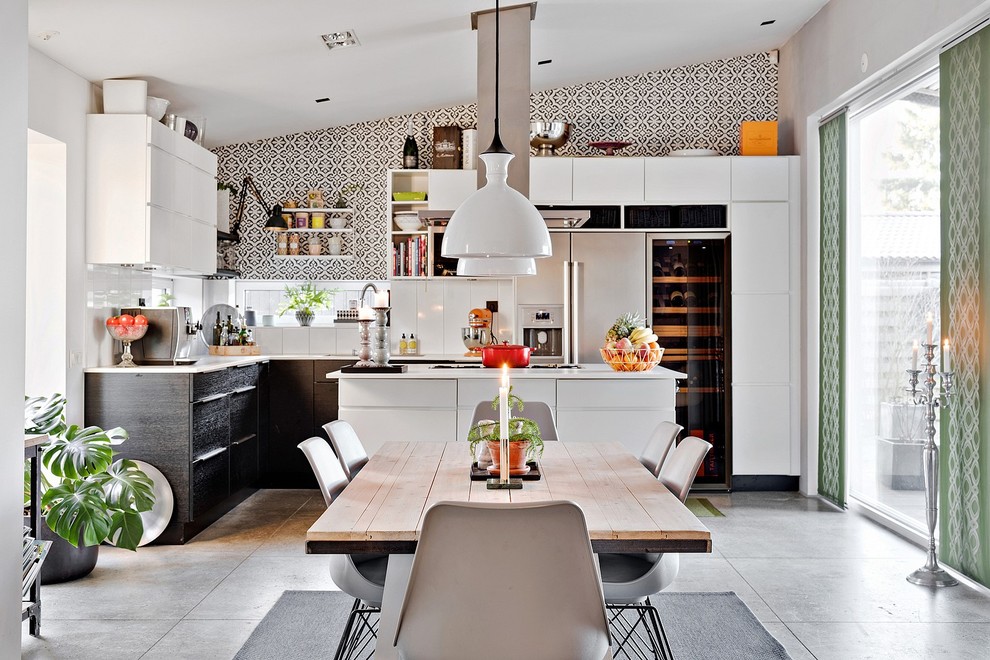 Medium sized contemporary open plan kitchen in Malmo with flat-panel cabinets, white splashback, stainless steel appliances and an island.
