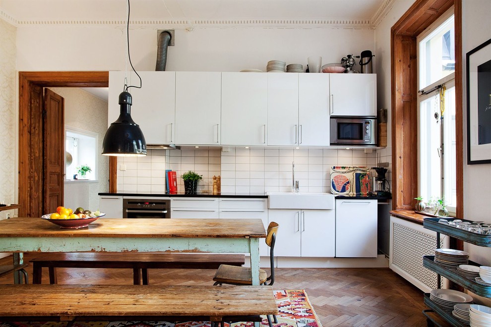 Inspiration för ett mellanstort skandinaviskt linjärt kök, med ljust trägolv, släta luckor, vita skåp, stänkskydd i porslinskakel och rostfria vitvaror