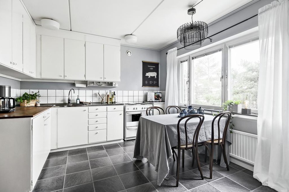 Inspiration för minimalistiska grått kök, med släta luckor, vita skåp, vitt stänkskydd, vita vitvaror och grått golv