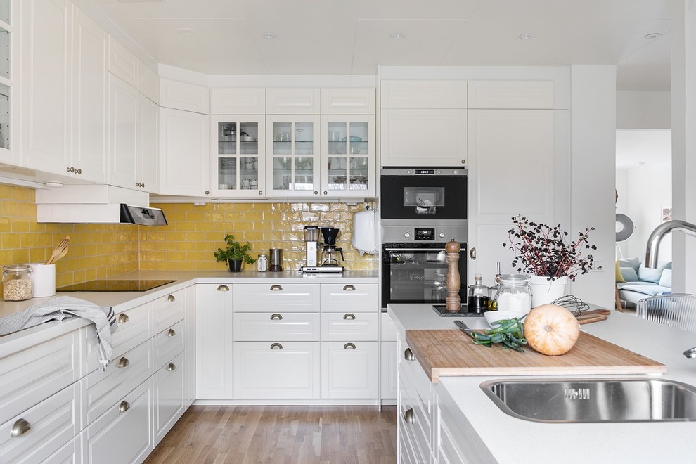 Immagine di una cucina scandinava con lavello a doppia vasca, top in laminato, elettrodomestici in acciaio inossidabile e top bianco