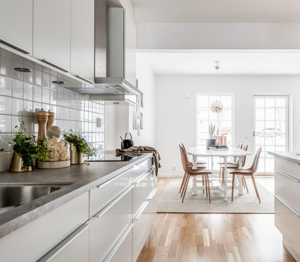 Inspiration for a scandinavian galley kitchen/diner in Other with flat-panel cabinets, white cabinets, white splashback, porcelain splashback, laminate floors, grey worktops, a submerged sink, no island and beige floors.