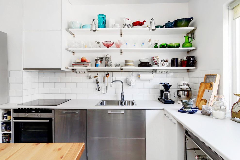 Geschlossene Eklektische Küche in L-Form mit Waschbecken, offenen Schränken, weißen Schränken, Laminat-Arbeitsplatte, weißen Elektrogeräten und Kücheninsel in Örebro