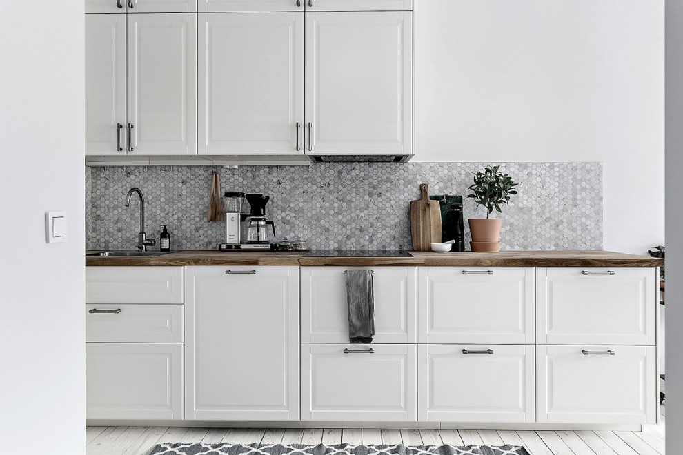 Idéer för ett stort minimalistiskt linjärt kök, med en nedsänkt diskho, luckor med upphöjd panel, vita skåp, grått stänkskydd, stänkskydd i mosaik och målat trägolv