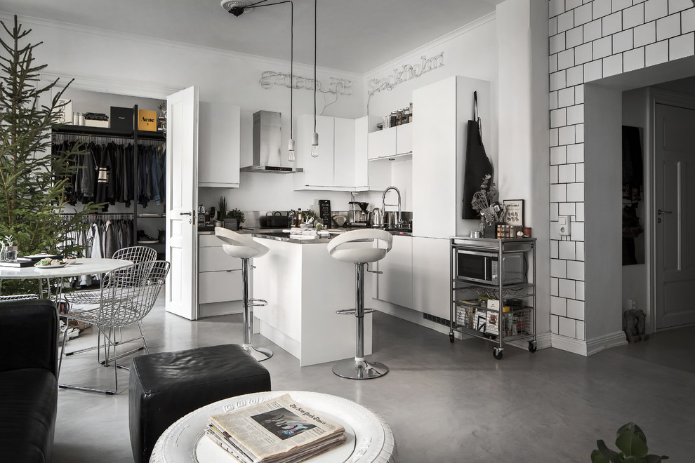 Immagine di una cucina industriale di medie dimensioni con ante lisce, ante bianche, top in acciaio inossidabile e pavimento in cemento