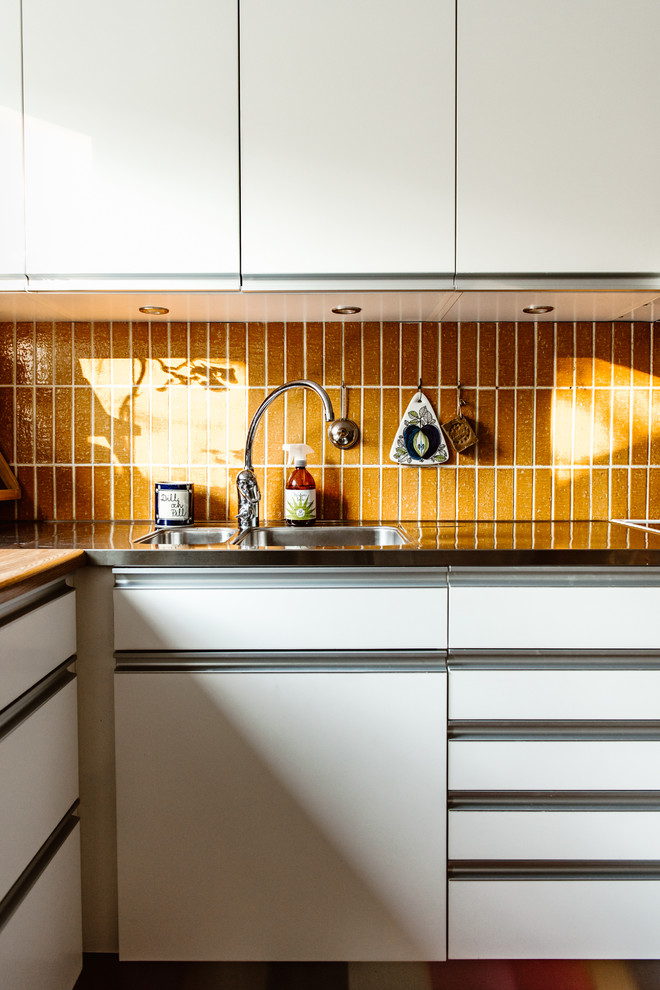 Design ideas for a small midcentury kitchen in Stockholm with orange splashback.