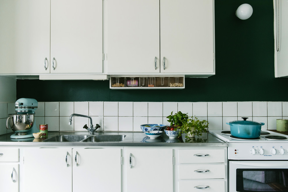 Photo of a small scandinavian single-wall enclosed kitchen in Stockholm with flat-panel cabinets, white cabinets, white splashback and no island.