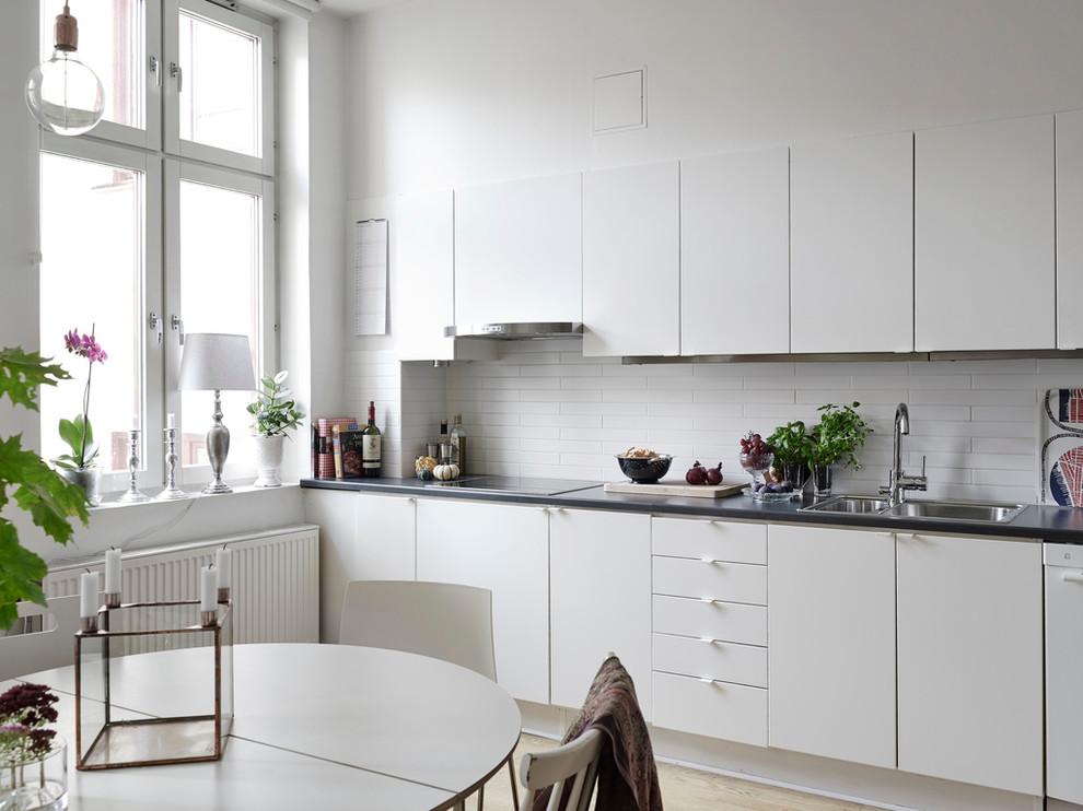 Esempio di una cucina scandinava di medie dimensioni con lavello a doppia vasca, ante lisce, ante bianche, top in acciaio inossidabile, elettrodomestici bianchi, parquet chiaro e nessuna isola