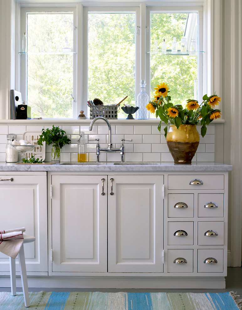 Immagine di una cucina lineare tradizionale di medie dimensioni con lavello a doppia vasca, ante con bugna sagomata, ante bianche, top in marmo e nessuna isola