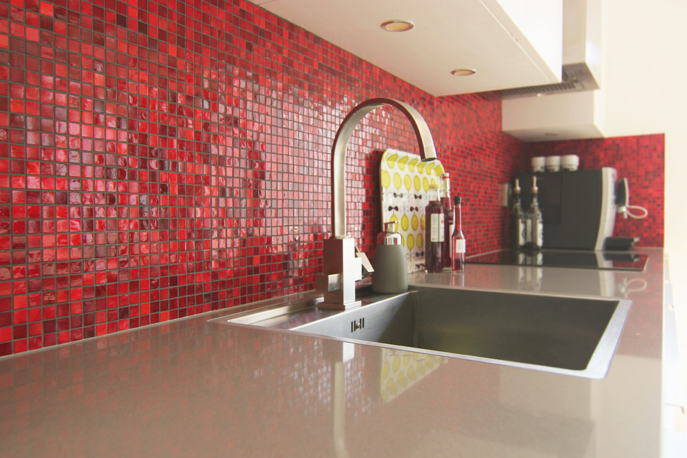 Idéer för ett kök, med en nedsänkt diskho, vita skåp, rött stänkskydd och stänkskydd i mosaik