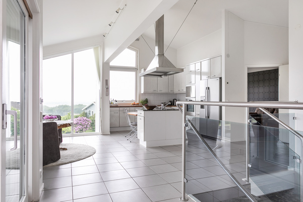 Modern inredning av ett stort l-kök, med släta luckor, vita skåp, en köksö och grått golv