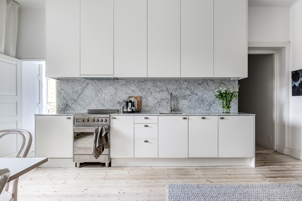 Einzeilige, Mittelgroße Nordische Küche ohne Insel mit flächenbündigen Schrankfronten, weißen Schränken und hellem Holzboden in Stockholm