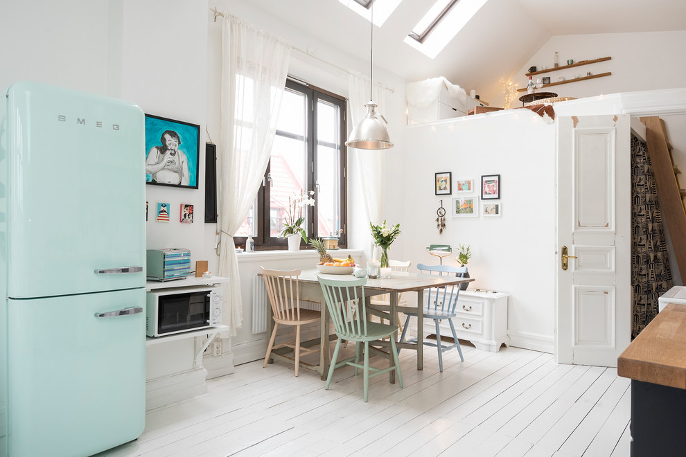 Example of a mid-sized danish painted wood floor open concept kitchen design in Malmo with a farmhouse sink, colored appliances, no island, raised-panel cabinets, white cabinets and wood countertops