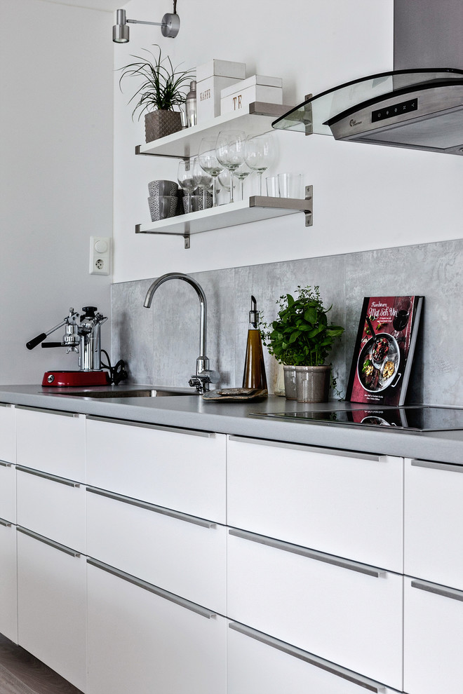 Einzeilige, Mittelgroße Nordische Küche ohne Insel mit flächenbündigen Schrankfronten, weißen Schränken, Küchenrückwand in Grau, Küchengeräten aus Edelstahl und Waschbecken in Stockholm