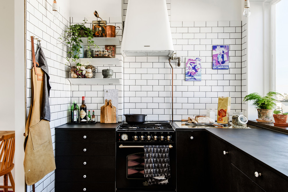 Bild på ett mellanstort skandinaviskt l-kök, med släta luckor, vitt stänkskydd, stänkskydd i tunnelbanekakel och svarta vitvaror