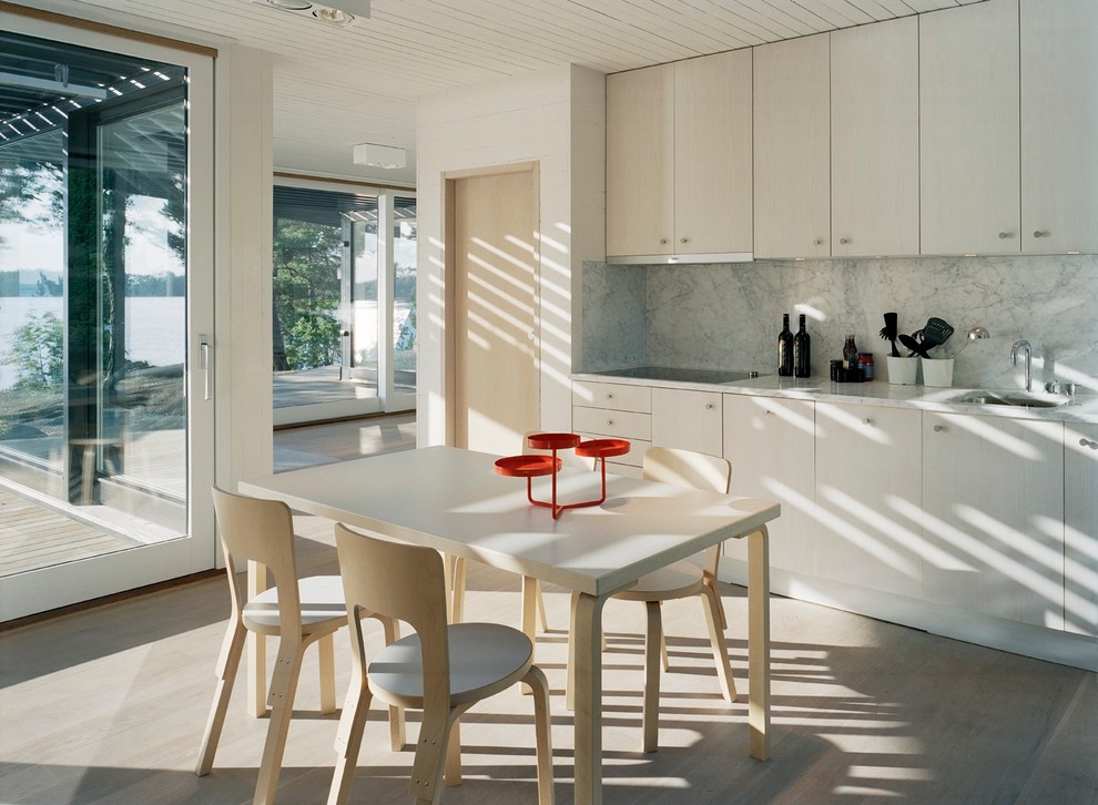 Idéer för att renovera ett stort minimalistiskt linjärt kök med öppen planlösning, med en integrerad diskho, släta luckor, skåp i ljust trä, marmorbänkskiva, grått stänkskydd, integrerade vitvaror och ljust trägolv