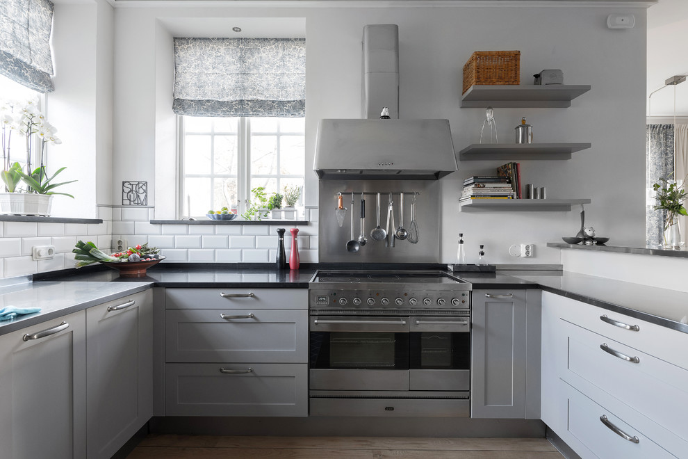 This is an example of a medium sized scandinavian u-shaped kitchen in Stockholm with recessed-panel cabinets, white cabinets and no island.