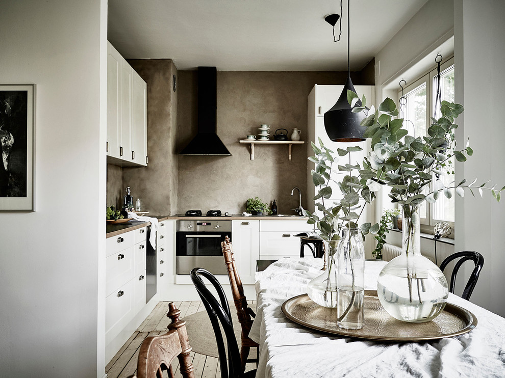 На фото: кухня среднего размера в скандинавском стиле с фасадами с утопленной филенкой и белыми фасадами с