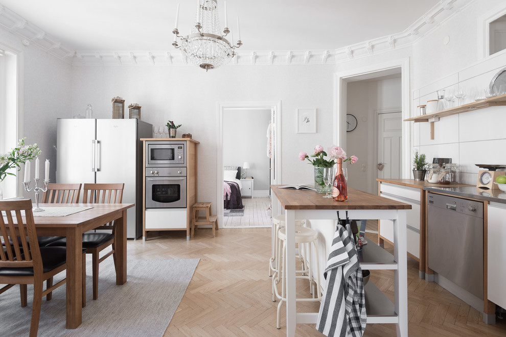 Bild på ett mellanstort minimalistiskt kök och matrum, med öppna hyllor, träbänkskiva, vitt stänkskydd, stänkskydd i porslinskakel, en köksö, rostfria vitvaror, ljust trägolv och beiget golv