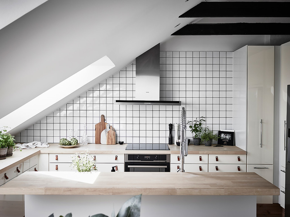 Diseño de cocinas en L escandinava pequeña cerrada con armarios con paneles lisos, puertas de armario blancas, encimera de madera, salpicadero blanco y una isla