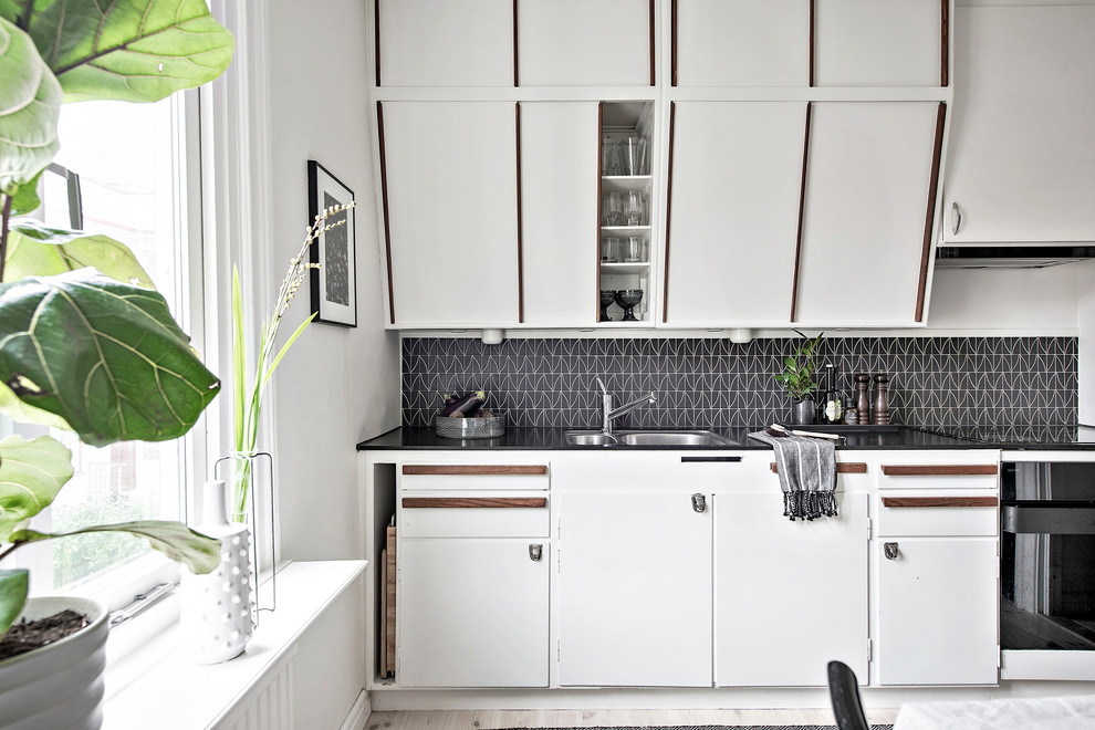 Diseño de cocina comedor lineal vintage sin isla con armarios con paneles lisos, puertas de armario blancas y salpicadero negro