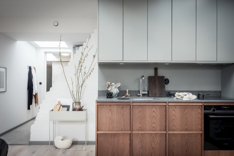 Idéer för att renovera ett mellanstort skandinaviskt grå grått kök, med en undermonterad diskho, släta luckor, skåp i mellenmörkt trä och beiget golv