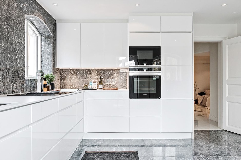 Bild på ett avskilt, mellanstort funkis l-kök, med släta luckor, vita skåp, grått golv, marmorgolv, grått stänkskydd och svarta vitvaror
