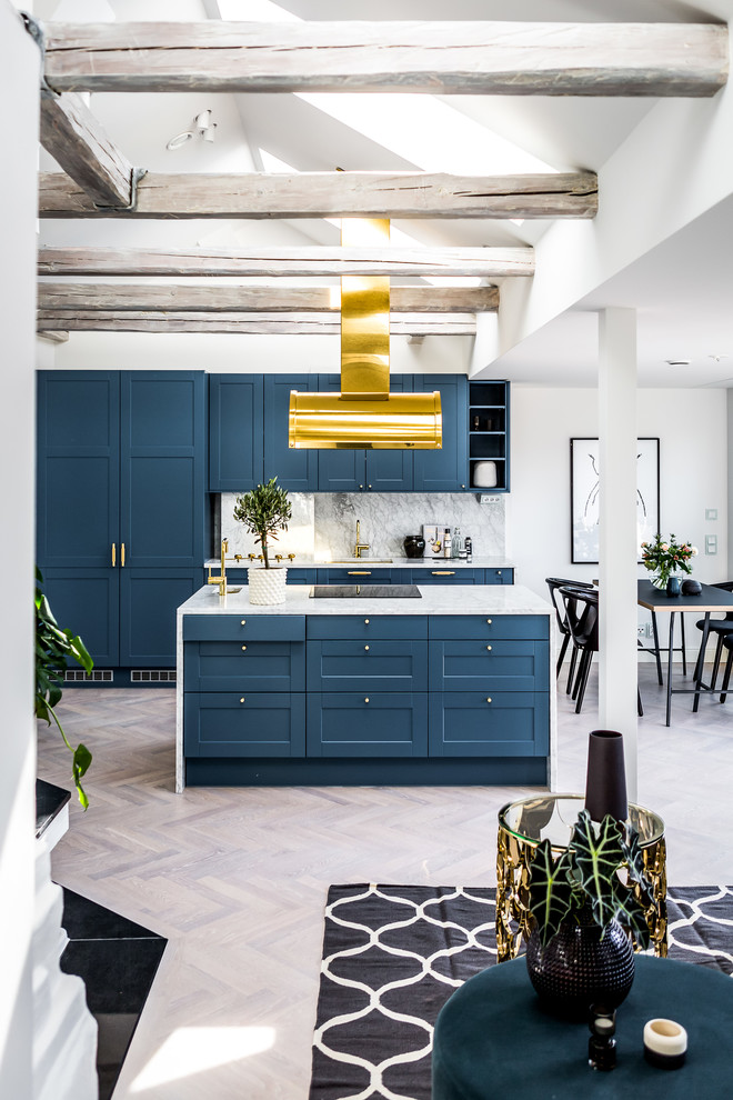 Bild på ett funkis kök med öppen planlösning, med blå skåp, marmorbänkskiva, vitt stänkskydd, stänkskydd i marmor, integrerade vitvaror, ljust trägolv, en köksö och skåp i shakerstil