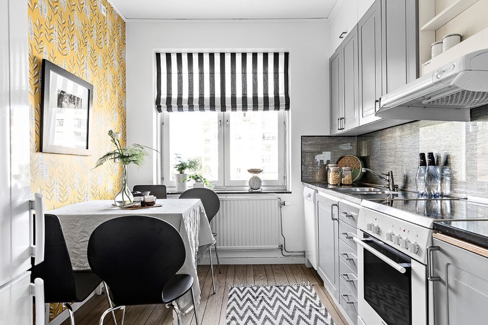 Пример оригинального дизайна: кухня в скандинавском стиле с обеденным столом, двойной мойкой, серыми фасадами, серым фартуком, белой техникой, темным паркетным полом, коричневым полом и обоями на стенах без острова