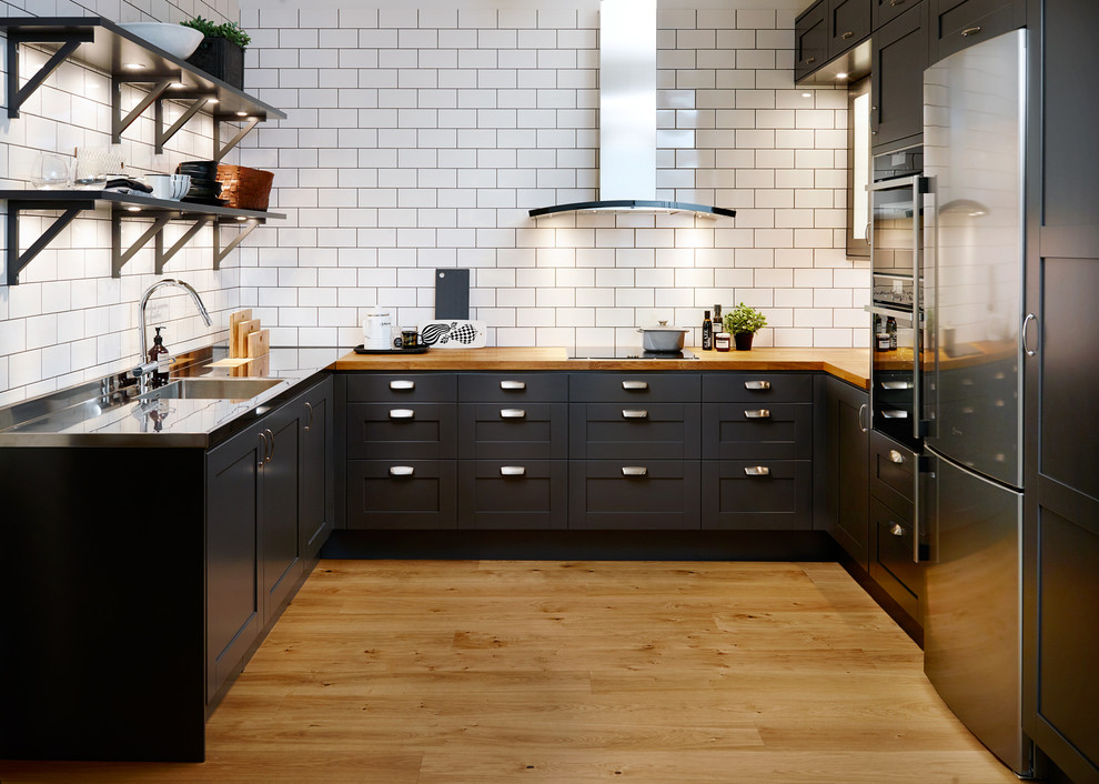 Medium sized traditional u-shaped kitchen in Stockholm with a single-bowl sink, black cabinets, wood worktops, stainless steel appliances, light hardwood flooring, no island and shaker cabinets.