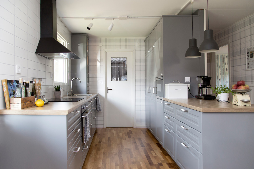 Nordisk inredning av ett mellanstort kök och matrum, med en dubbel diskho, grå skåp, laminatbänkskiva, mellanmörkt trägolv och en köksö