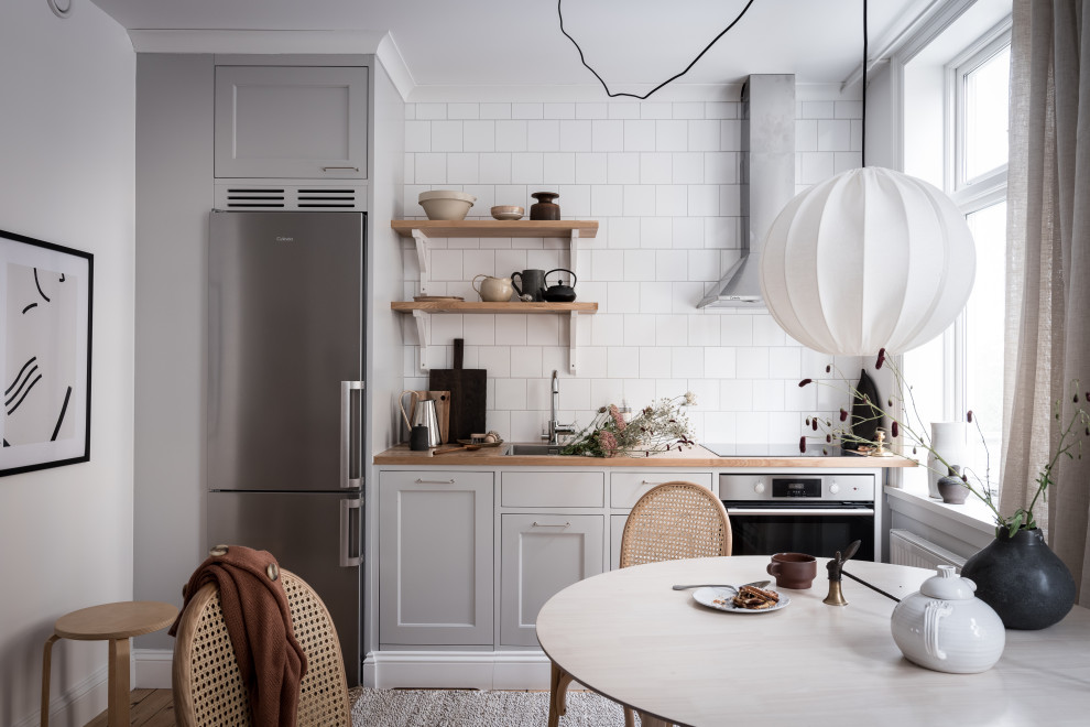 Idéer för ett litet minimalistiskt beige linjärt kök och matrum, med en nedsänkt diskho, skåp i shakerstil, grå skåp, träbänkskiva, vitt stänkskydd, mellanmörkt trägolv och brunt golv