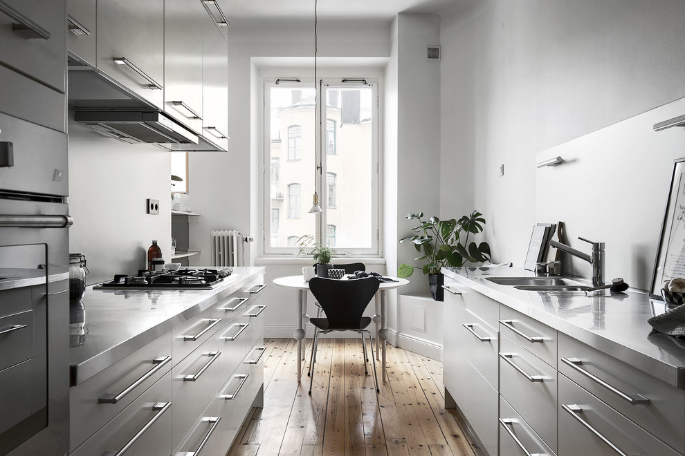 Источник вдохновения для домашнего уюта: параллельная, серо-белая кухня в скандинавском стиле с обеденным столом, двойной мойкой, плоскими фасадами, серыми фасадами, светлым паркетным полом, бежевым полом и окном